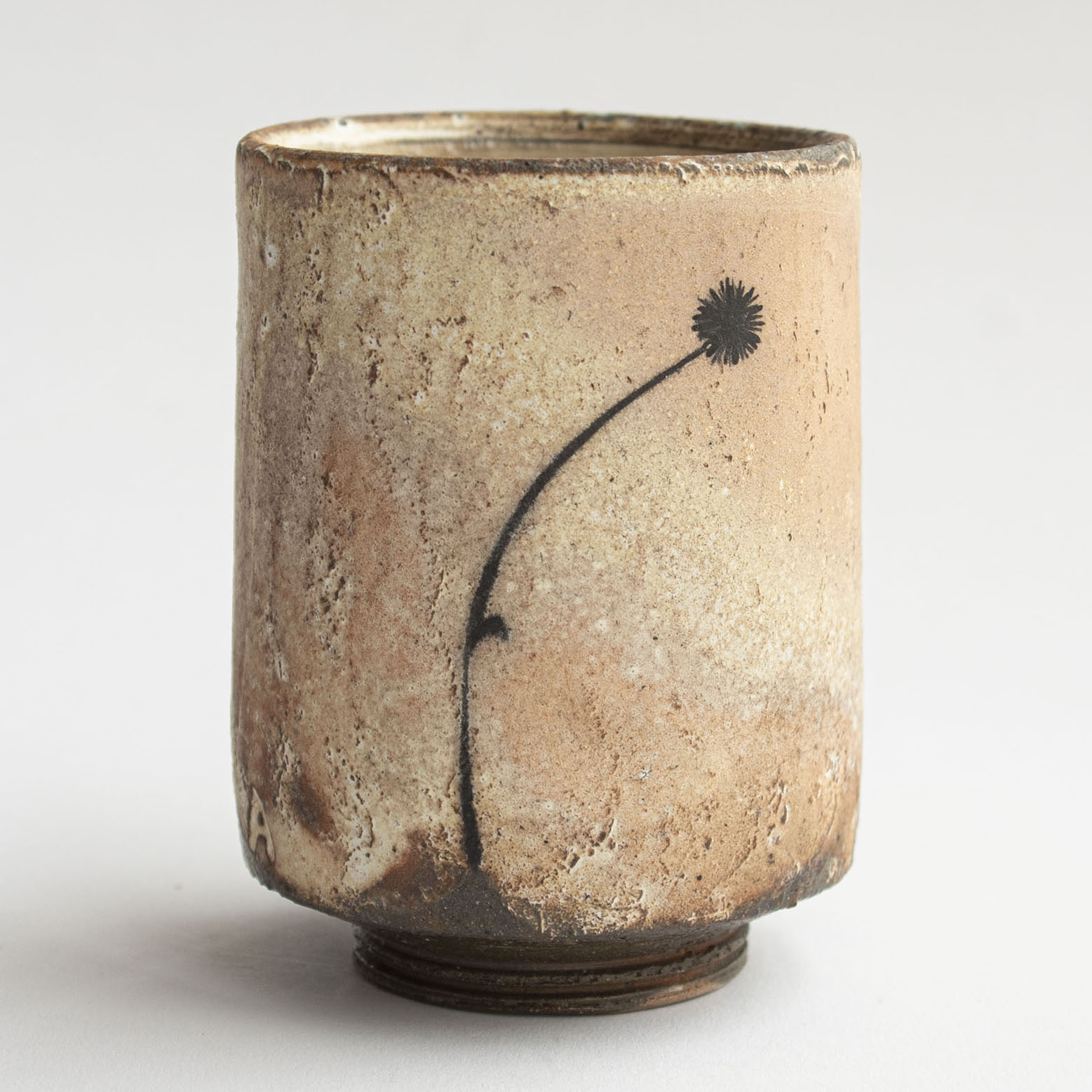 tan/pink ceramic cup by Ashton Keen decorated with black silhouette of a flower.