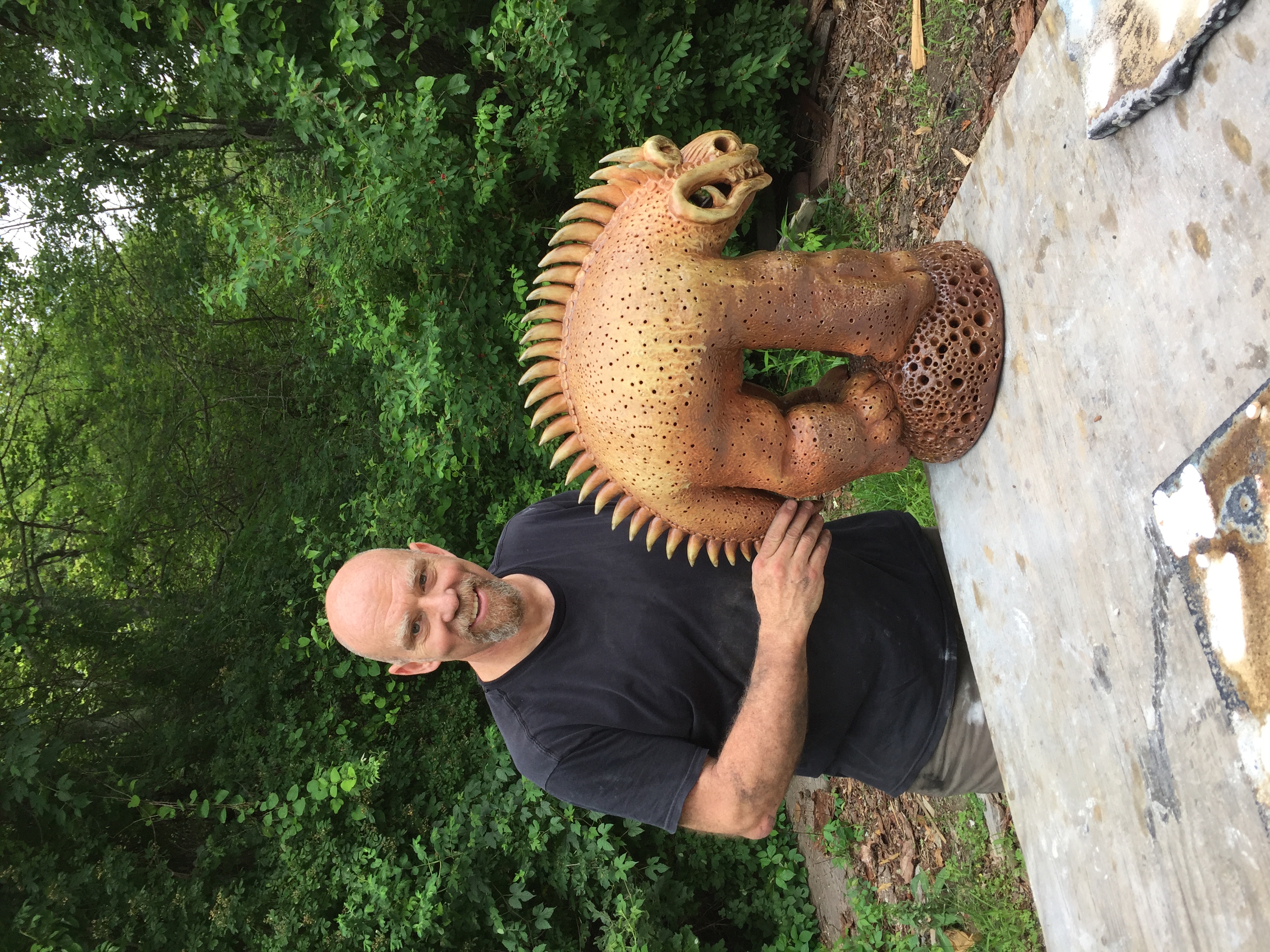 Steve Murphy standing beside one of his clay beast sculptures