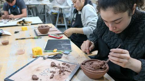 a student works on a red clay oil lamp
