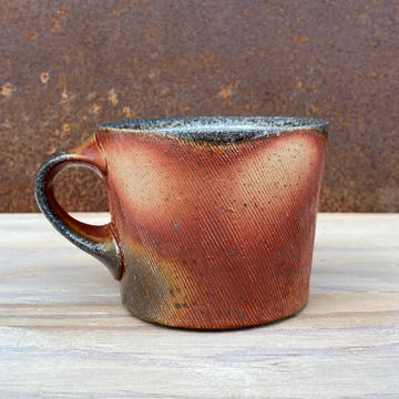 ceramic mug with orange and white and brown variations in surface color from atmospheric firing process 