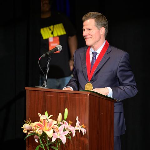 Bill Rauch standing at podium