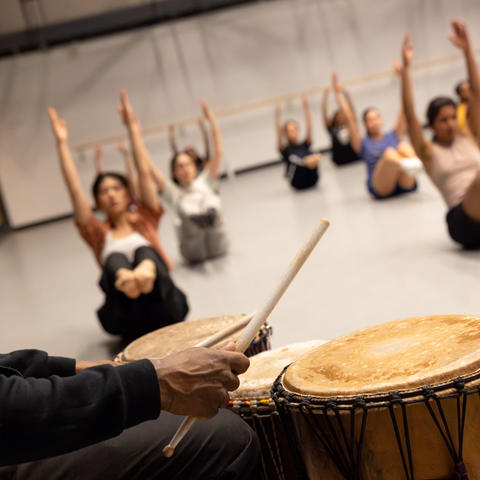 Students in a floor exercise in the background with a drummer in the foreground. 