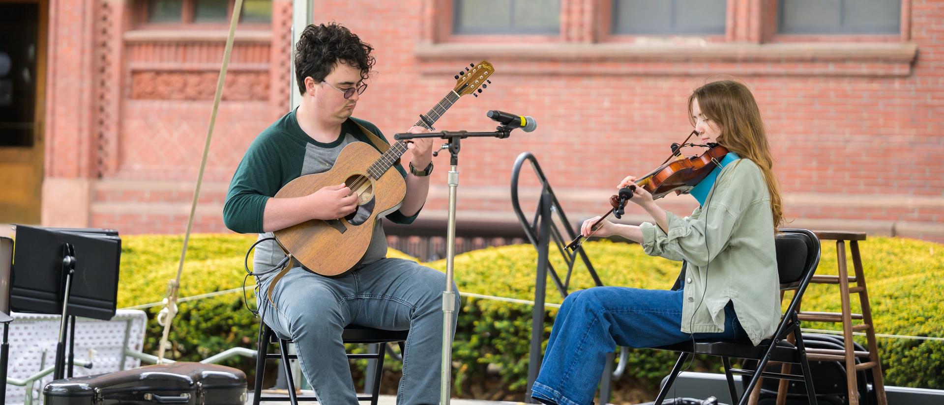 two musicians on stage with guitar and violin