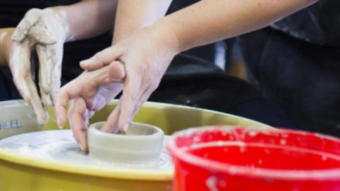 two pairs of hands at a potter's wheel - teacher and student