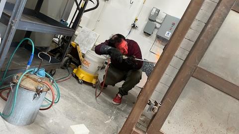 a person crouching down to spray soda into a glowing red kiln.