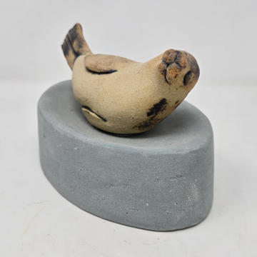 a clay sculpture of a seal curled in a banana shape