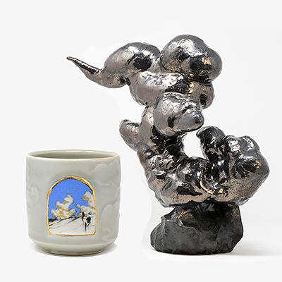 Two artworks by by Deighton Abrams side by side on a white background: A porcelain cup with cloud decoration and gold luster, and a sculpture metallic black-glazed cloud sculpture