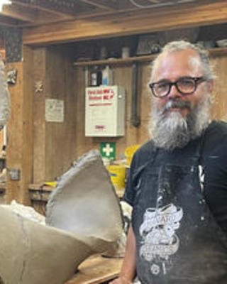 Nik Putnam with ceramic sculpture in a studio setting.